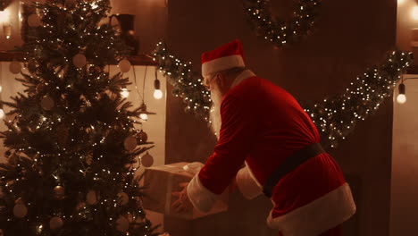 Santa-Claus-brings-gifts-under-the-Christmas-tree-for-children.-Give-gifts-to-children-on-Christmas-night.-Santa-puts-a-gift-under-the-Christmas-tree.-High-quality-4k-footage