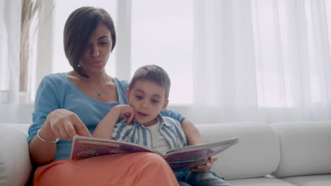 Feliz-Madre-E-Hijo-Leyendo-Un-Libro-Riéndose-En-La-Cama.-Familia-Feliz,-Madre-E-Hijo,-Hijo,-Lectura,-Tenencia,-Libro,-Acostado,-En-Cama,-Sonriente,-Mamá,-Niñera