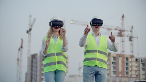 Two-inspectors-of-the-future-on-the-construction-site-use-virtual-reality-glasses-on-the-background-of-buildings-and-cranes