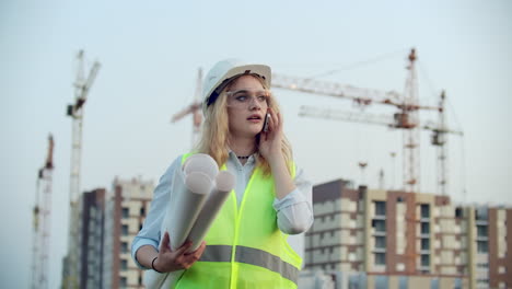 Dialogue-on-the-phone-a-woman-in-a-helmet-on-the-background-of-construction-discusses-with-the-Director-of-the-construction-site-of-the-building.