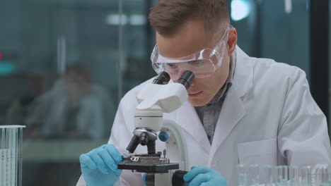 scientist-man-is-exploring-vaccine-from-coronavirus-in-laboratory-looking-into-microscope-apparatus-research-of-curing-from-covid-19