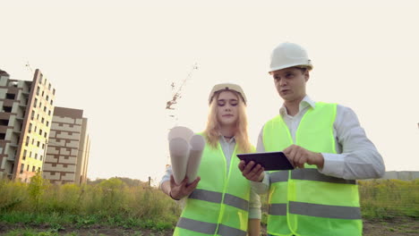 Ein-Erwachsener-Ingenieur-Und-Eine-Architektin-Verwenden-Im-Betrieb-Ein-Tablet.-Sie-Schreiben-Eine-Nachricht-Oder-Prüfen-Eine-Zeichnung.-Im-Hintergrund-Ist-Ein-Gebäude-Zu-Sehen.-Sehen-Sie-Sich-Die-Umgebung-Und-Zeichnungen-An,-Um-Abgeschlossene-Und-Geplante-Bauarbeiten-Zu-überprüfen.-Die-Arbeit-Eines-Krans