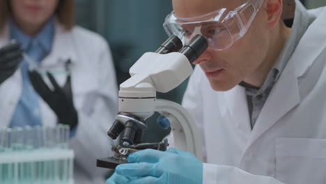 Los-Estudiantes-Estudian-Química-En-La-Universidad-Trabajando-Con-Reactivos-Y-Microscopio-En-Clase-Retrato-De-Un-Joven-En-Un-Laboratorio-Científico