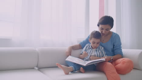 Feliz-Madre-E-Hijo-Leyendo-Un-Libro-Riéndose-En-La-Cama.-Familia-Feliz,-Madre-E-Hijo,-Hijo,-Lectura,-Tenencia,-Libro,-Acostado,-En-Cama,-Sonriente,-Mamá,-Niñera