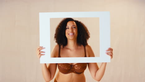 Studio-Shot-Of-Confident-Natural-Woman-In-Underwear-Making-Funny-Faces-In-Picture-Frame
