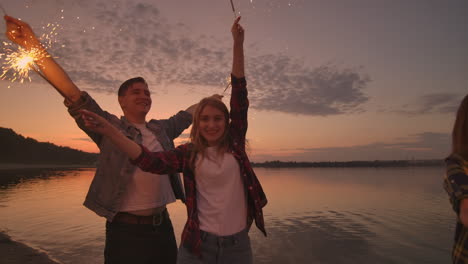 Group-of-friends-having-fun-running-on-the-beach-with-sparklers