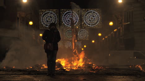 Eine-Weibliche-Figur,-Die-In-Der-Herbstnacht-Neben-Dem-Erlöschenden-Lagerfeuer-Steht