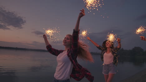 Un-Grupo-De-Amigos,-Hombres-Y-Mujeres,-Celebran-Las-Vacaciones-En-La-Playa-Con-Bengalas-Y-Fuegos-Artificiales.-Fiesta-De-Celebración-Nocturna-En-Cámara-Lenta-En-La-Playa.