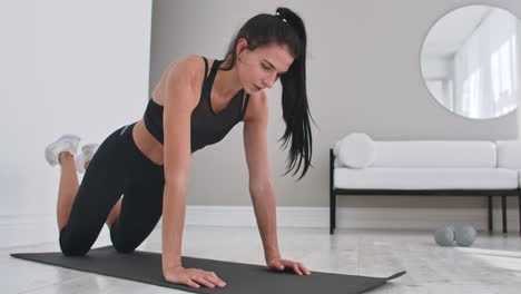 Young-sexy-brunette-woman-in-sportswear-doing-side-plank-exercise-shifts-hands-while-kneeling-in-white-beautiful-apartment-interior