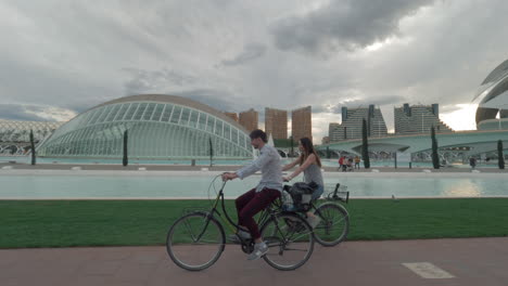 Ein-Paar-Fährt-Mit-Dem-Fahrrad-Entlang-Der-Modernen-Aussicht-Auf-Valencia