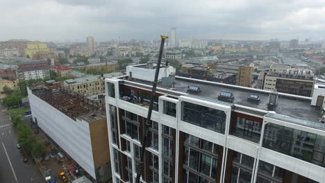 Crane-lifting-glass-panels-on-building-upper-floor-aerial