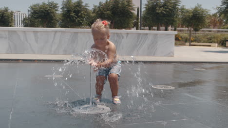 Little-child-playing-with-water-jet-of-street-fountain