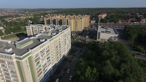 Una-Vista-Aérea-De-Edificios-De-Varios-Pisos-Junto-Al-Bosque-Verde-Contra-El-Cielo-Azul