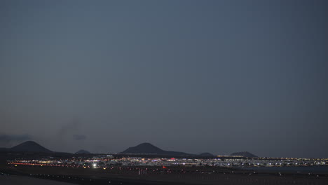 A-beautiful-night-view-with-a-plane-taking-off-over-the-night-city-and-dark-mountains