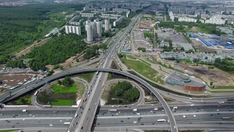 Una-Vista-Aérea-De-Un-Enorme-Y-Transitado-Cruce-De-Carreteras-En-Medio-Del-Verde-Paisaje-Urbano