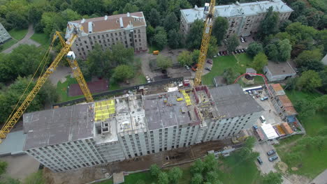 Aerial-shot-of-workers-and-cranes-on-construction-site-with-apartment-complex