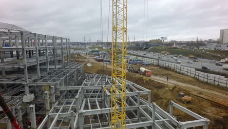 A-vertical-inspection-of-a-construction-crane-against-the-building-frame-and-a-busy-highway