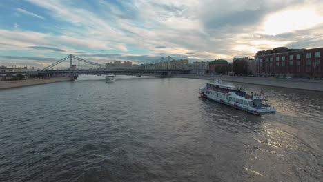 Eine-Luftaufnahme-Von-Weißen-Booten,-Die-Auf-Dem-Fluss-Segeln,-Umgeben-Von-Der-Stadtlandschaft