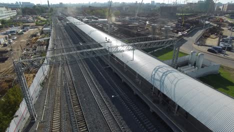 Tren-Eléctrico-Que-Llega-A-La-Estación-En-Las-Afueras-De-La-Ciudad-Vista-Aérea