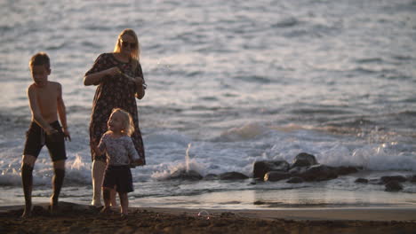 Mutter-Mit-Verspielten-Kindern-Im-Familienurlaub-Am-Schwarzen-Sandstrand