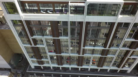 Modern-apartment-house-with-street-reflection-in-glassy-facade-aerial