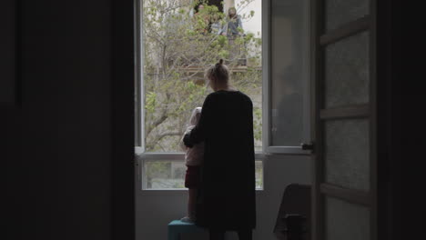 Mum-with-little-daughter-by-open-window-during-coronavirus-lockdown