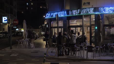 Calle-Nocturna-Con-Gente-Despidiéndose-Cerca-Del-Café-Valencia