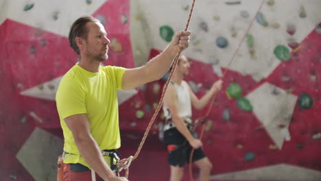 Man-belaying-another-climber-with-rope.-Top-view-of-young-athletic-man-belaying-and-watching-another-climber-with-rope.-Summer-time.-Climbing-equipment.