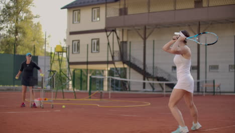 Eine-Tennisspielerin-übt-Das-Schlagen-Des-Balls,-Während-Der-Trainer-In-Zeitlupe-Mit-Einem-Schläger-Auf-Den-Ball-Schlägt.-Training-Einer-Professionellen-Tennisspielerin.