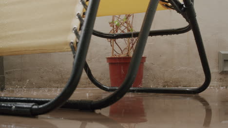 Ein-Gelber-Stuhl-Und-Eine-Blume-Werden-Im-Regen-Auf-Dem-Balkon-Nass