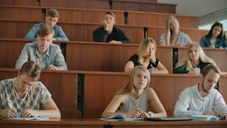 En-El-Aula,-Estudiantes-Multiétnicos-Escuchando-A-Un-Profesor-Y-Escribiendo-En-Cuadernos.-Los-Jóvenes-Inteligentes-Estudian-En-La-Universidad.