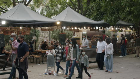 Gente-En-La-Calle-Con-Una-Cafetería-Exterior-Y-Un-Contenedor-De-Basura-Lleno