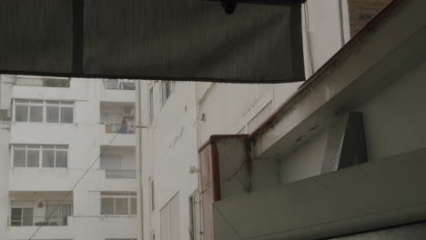 Eine-Frau-Steht-Auf-Dem-Balkon-Und-Blickt-In-Den-Regen