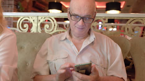 Senior-man-with-phone-in-the-restaurant