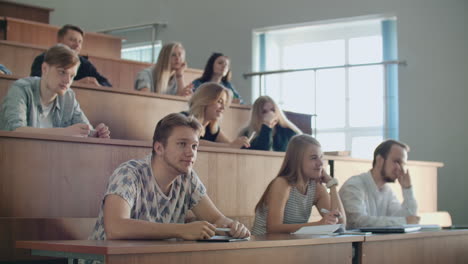 Los-Estudiantes-Modernos,-Hombres-Y-Mujeres,-Se-Sientan-En-Escritorios-En-Un-Aula-Grande-Y-Escriben-Notas-De-Clase.-Obtener-Una-Educación-Para-Una-Carrera-Exitosa