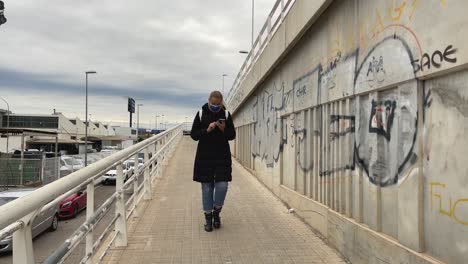 Woman-walking-in-a-city-district-splattered-with-graffiti