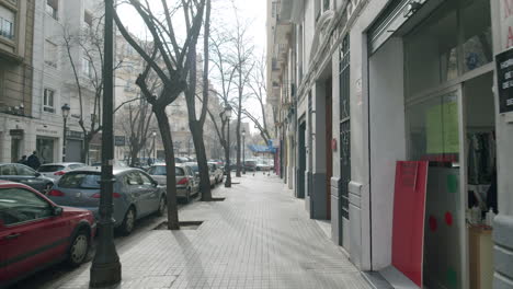 Empty-street-with-parked-cars-and-storefronts-in-sunny-morning-Valencia