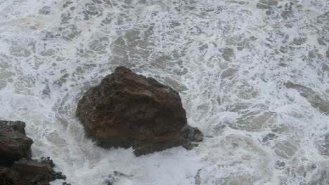 Foamy-ocean-water-and-big-coastal-rocks