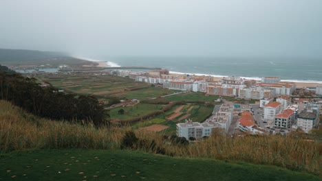 Vista-Panorámica-De-La-Playa-De-Nazaré-Con-Tierras-De-Cultivo-Y-Hoteles-Portugal