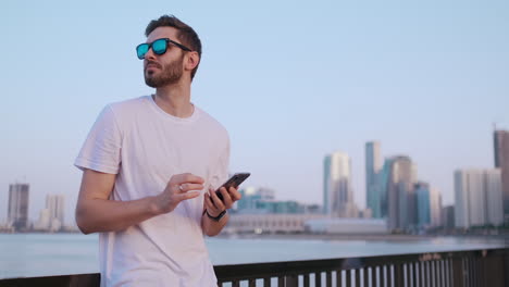 Camera-moves-around-handsome-young-man-as-he-uses-his-phone.-Portrait.-Blurred-background.