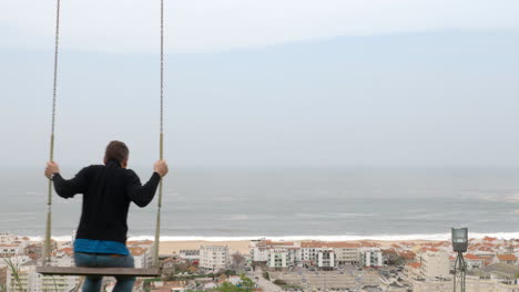 Mann-Schwingt-Auf-Dem-Hügel-Mit-Blick-Auf-Den-Ferienort-Und-Das-Meer-Nazare-In-Portugal