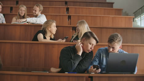 Cheerful-students-are-using-smartphones-and-chatting-during-break-between-lectures-at-university.-Modern-technology.-Cheerful-students-multiethnic-group-are