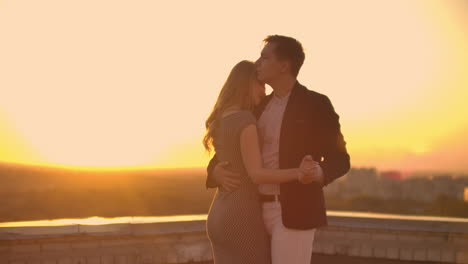 Two-lovers-embracing-dancing-on-top-of-a-skyscraper-overlooking-the-city-at-sunrise-sunset.-Romantic-setting