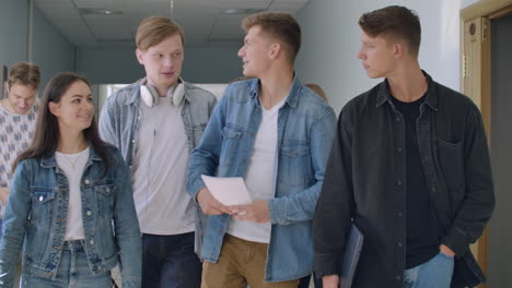 A-group-of-students-walk-along-the-corridor-of-the-university-school-college-communicate-talk-and-smile.-A-large-group-of-people-walking-in-the-hall-of-an-educational-institution-with-books-in-their-hands.