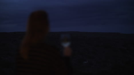 Lonely-woman-drinking-wine-and-looking-at-green-landscape-view-in-the-dusk