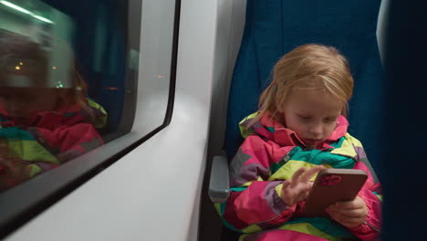 Little-girl-passenger-with-phone-traveling-by-train