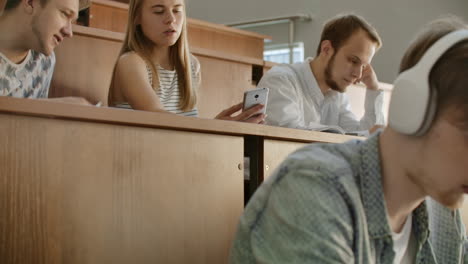 Chicas-Guapas,-Estudiantes,-Usan-Teléfonos-Inteligentes-Para-Mirar-La-Pantalla,-Hablar-Y-Reír-Sentadas-En-Los-Escritorios-De-La-Universidad.-Medios-Sociales-Internet-Millennials-Y-Concepto-De-Educación