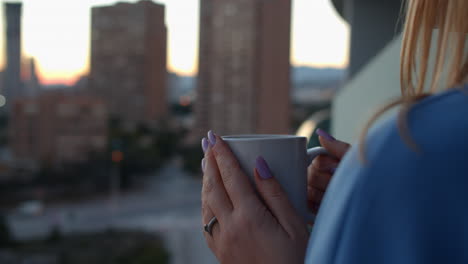 Woman-having-hot-tea-on-the-apartment-balcony-in-the-morning