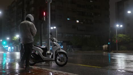 Scooter-driver-setting-off-under-the-rain-in-night-city