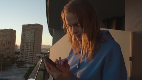 Frau-Auf-Einem-Balkon-Mit-Smartphone